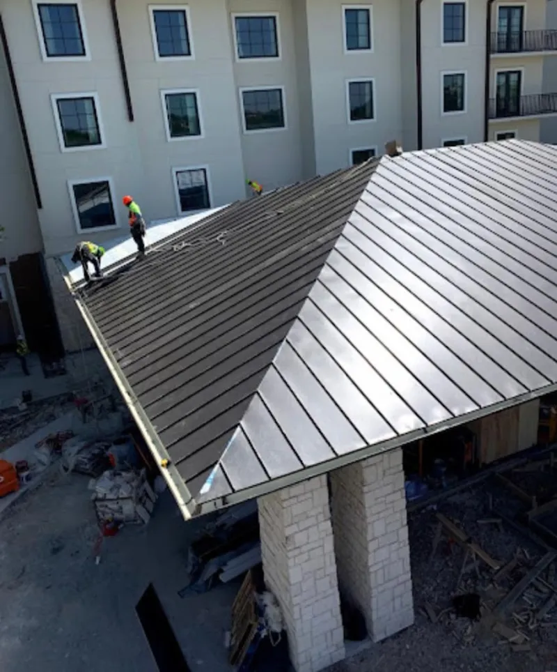 Crew installing standing seam metal roof panels on a commercial project in Akron